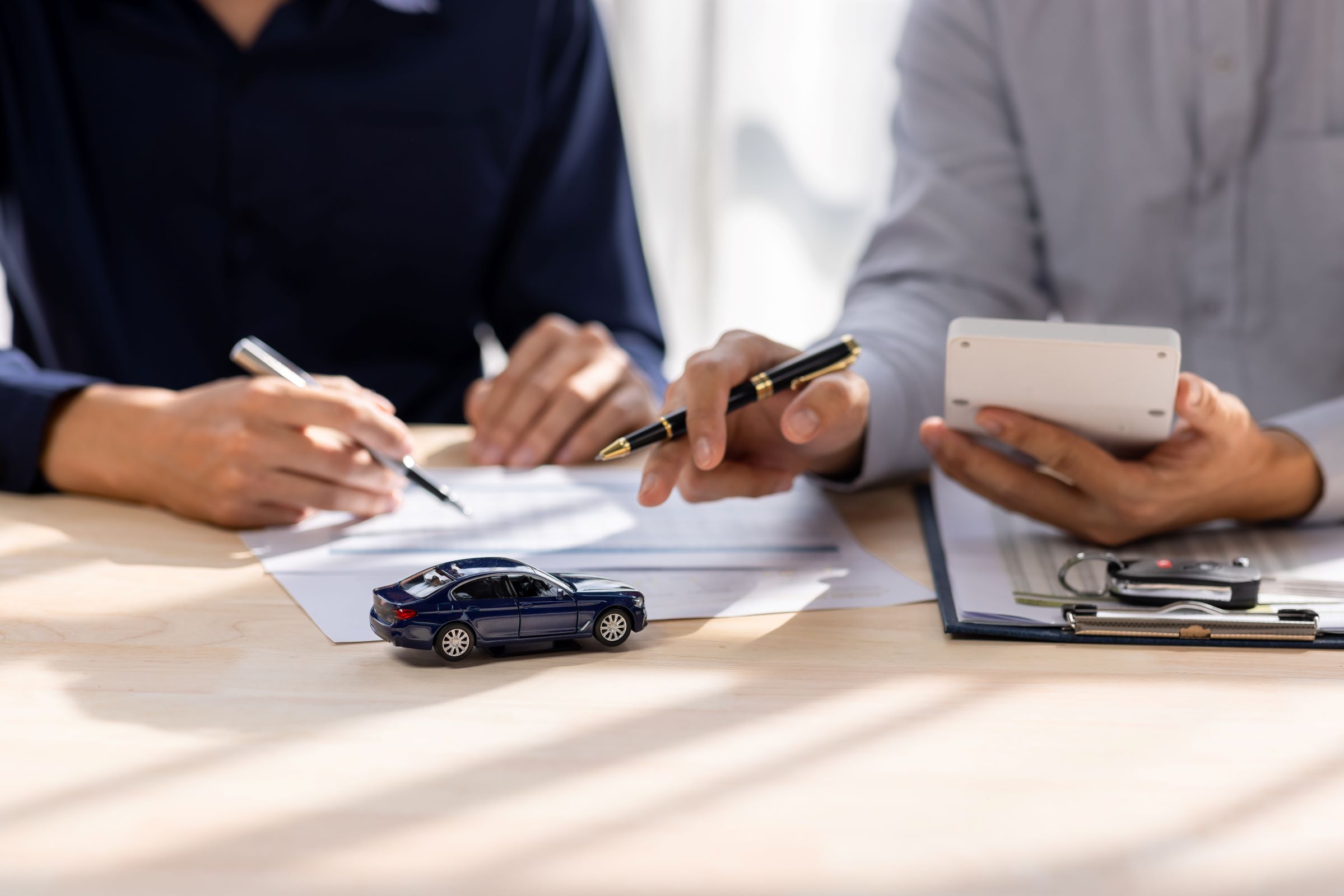 People looking over refinance forms. | Featured image for the Refinancing Your Car Loan Do’s and Don’ts Blog from Fido Finance.