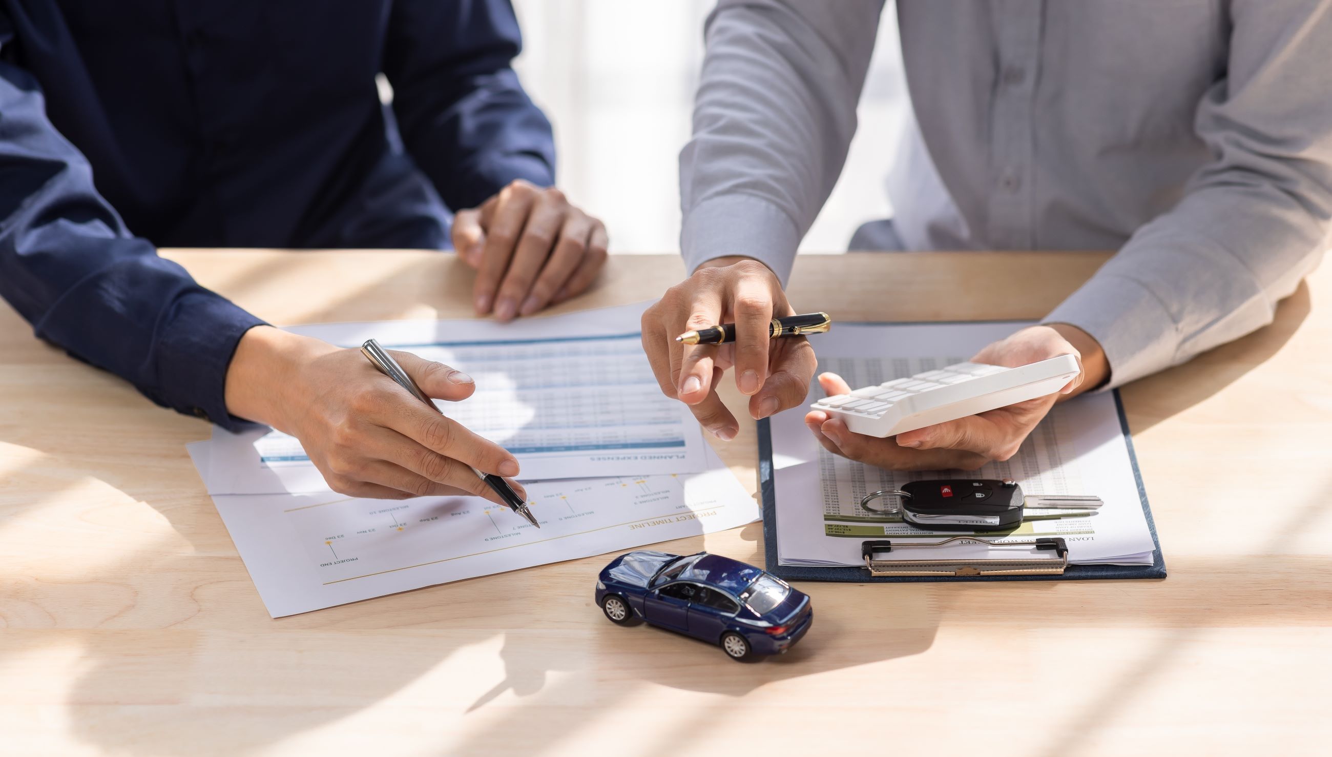 Two People Sitting at Table Discussing Finance | Featured image for the Understanding Car Loan Early Repayment Fees Blog from Fido Finance.