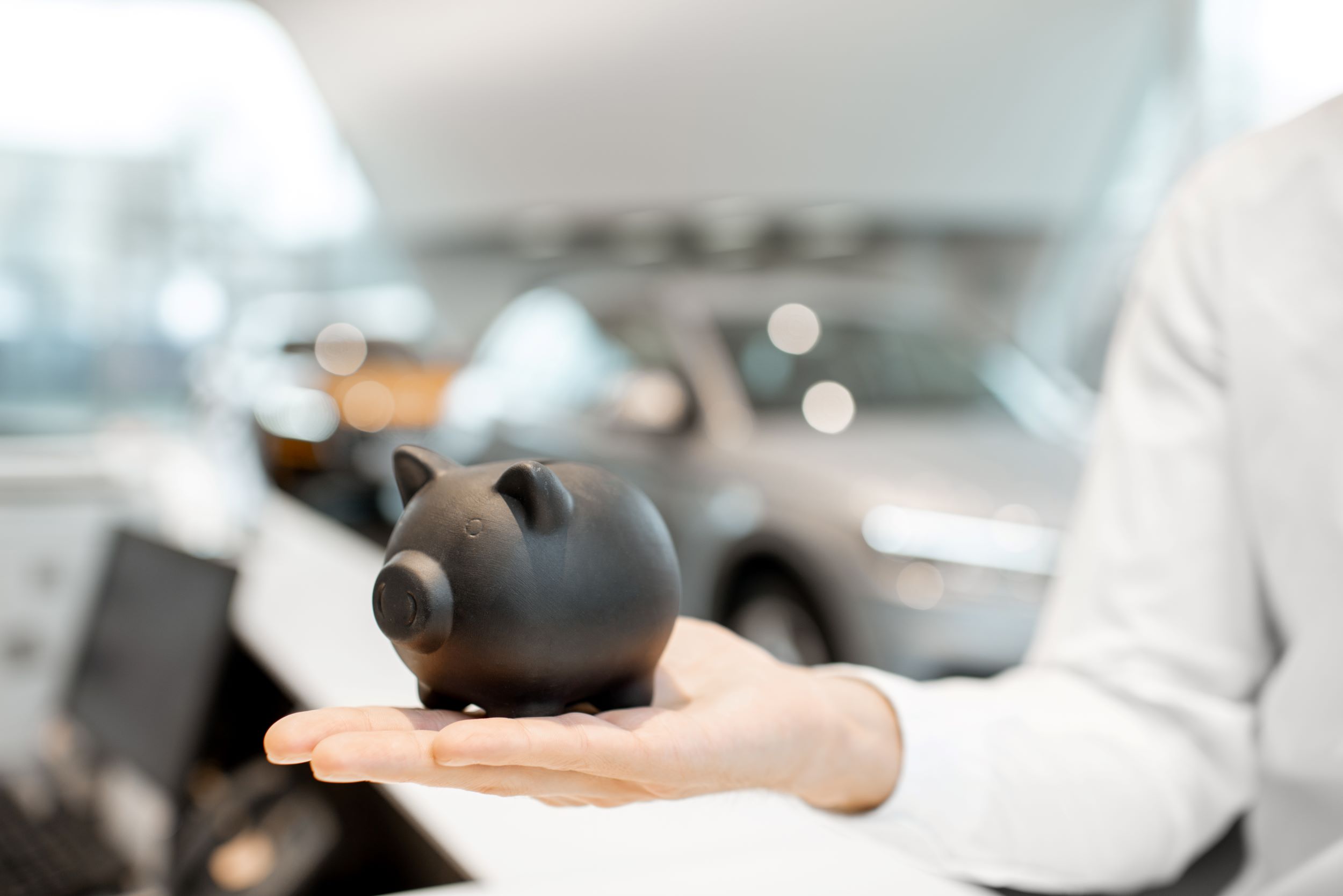 Piggy Bank On The Hand In The Car Showroom | Featured image for the Your Guide to Personal Loans Blog from Fido Finance.