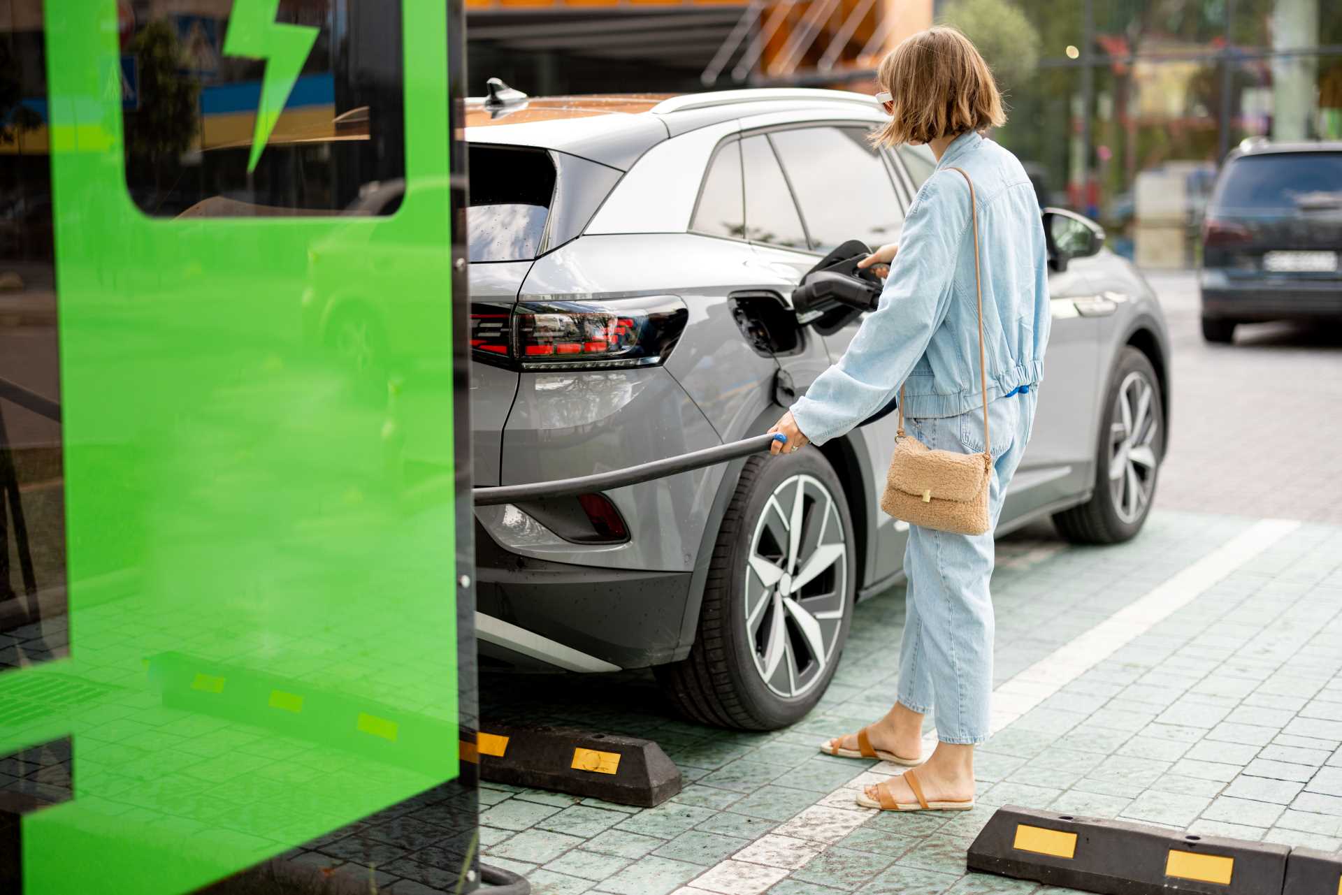Woman charging her electric car | Featured image for the Main Benefits of Electric Cars Blog from Fido Finance.