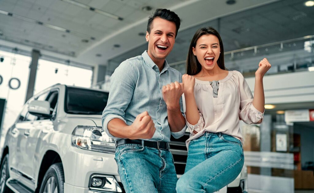 Happy young couple chooses and buying a new car | Featured image for the Best Time to Upgrade Car Guide Blog from Fido Finance.