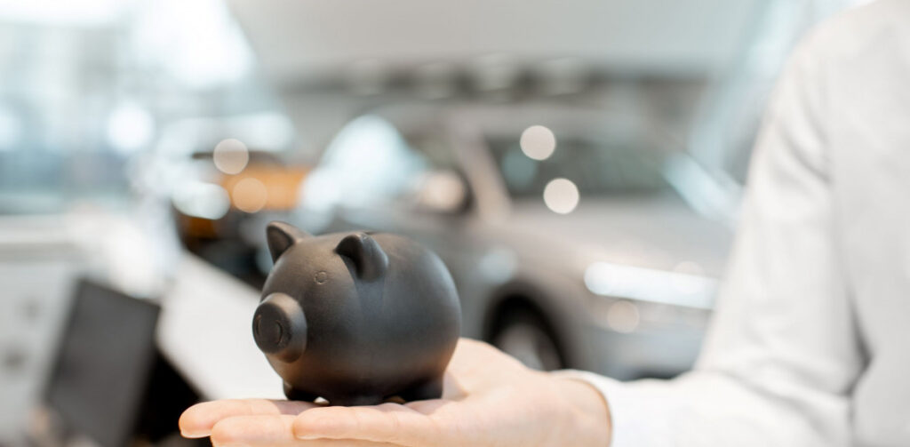Piggy Bank On The Hand In The Car Showroom | Featured image for the Your Guide to Personal Loans Blog from Fido Finance.