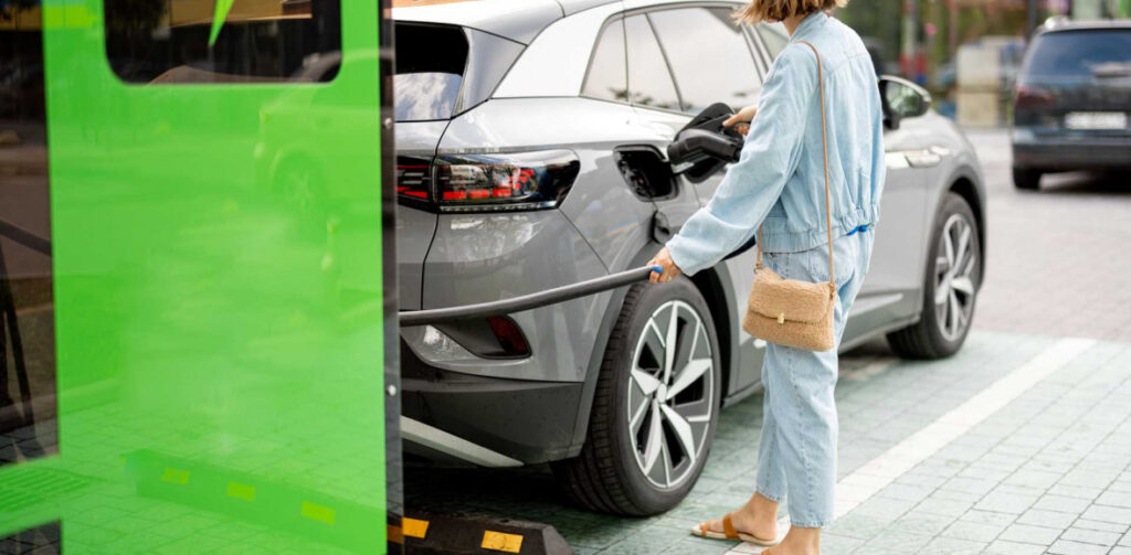 Woman charging her electric car | Featured image for the Main Benefits of Electric Cars Blog from Fido Finance.