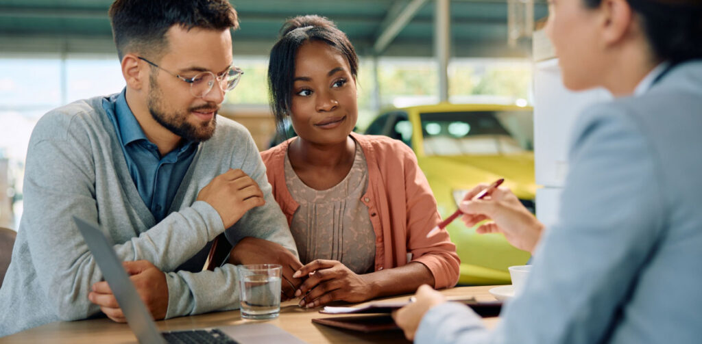 Young Multiracial Couple About To Sign Contract During A Meeting With Car Saleswoman | Featured image for the Our Top 6 Tips for Financing a Car with Bad Credit Blog from Fido Finance.